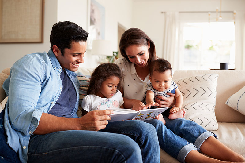 Young family of four reading a book