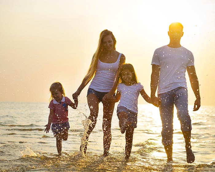 Happy Family Having Fun Running On Beach